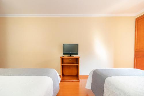a room with two beds and a television on a table at Ayenda La Antigua in Tunja