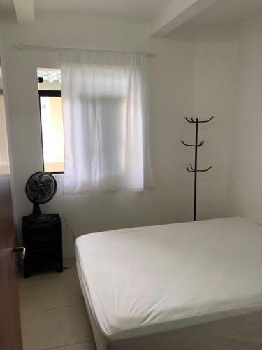 a white bedroom with a bed and a window at Apartamento Ilha do Coral in Palhoça