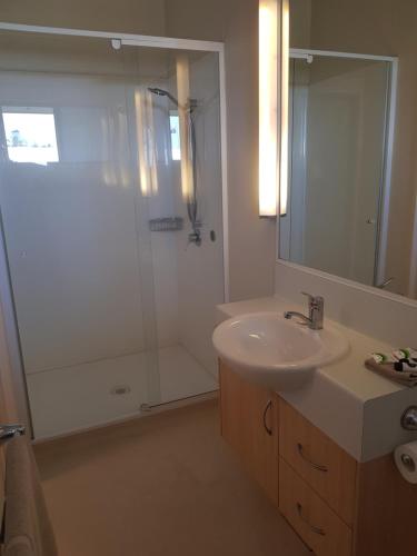 a bathroom with a sink and a shower with a mirror at Cardwell Beachcomber Motel & Tourist Park in Cardwell