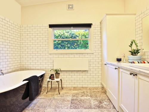 a bathroom with a bath tub and a window at Poppy Cottage in Exeter