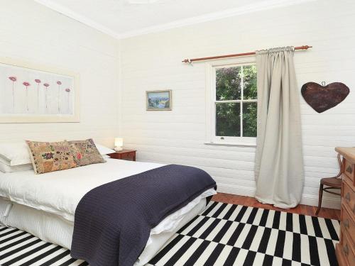un dormitorio con una cama y una ventana en Poppy Cottage, en Exeter