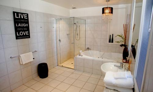 a bathroom with a shower and a tub and a sink at Hilltop Apartments Phillip Island in Cowes