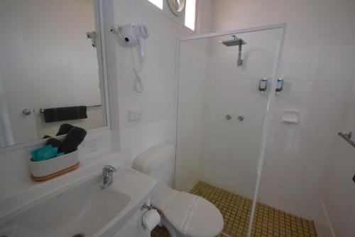 South Seas Motel في ميريمبولا: حمام أبيض مع دش ومرحاض