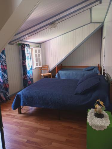 a bedroom with a blue bed in a attic at Auberge du Cap in Cilaos