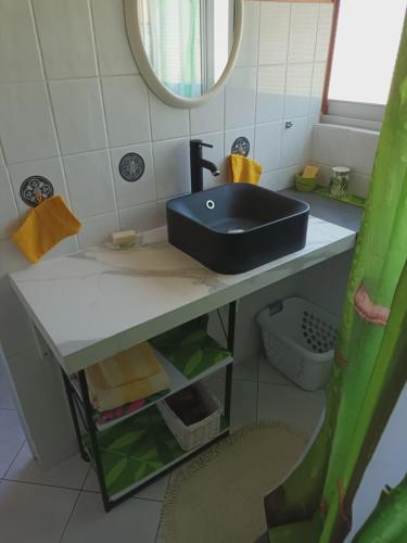 a bathroom with a black sink and a mirror at Auberge du Cap in Cilaos