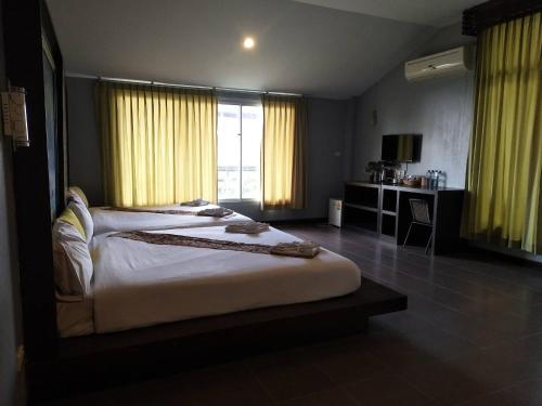 a bedroom with a large bed with yellow curtains at Krabi Home Town Boutique in Krabi town