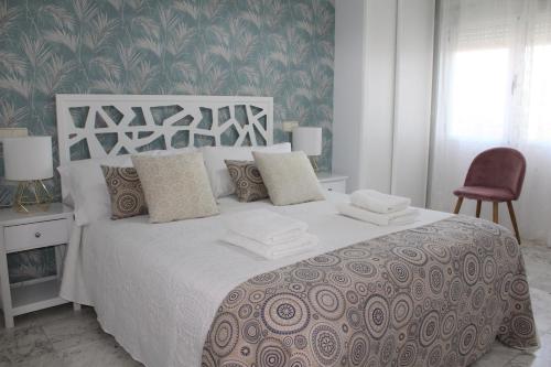 a bedroom with a large white bed with a red chair at Apartamento Vistas molineras in Consuegra