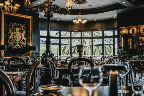 ein Restaurant mit Tischen, Stühlen und einem Kronleuchter in der Unterkunft Hotel Bellinzona Daylesford in Hepburn Springs