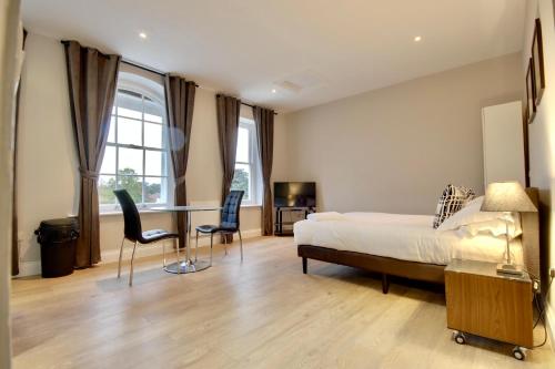 a bedroom with a bed and a table and chairs at Orange Grove Hotel & Gardens in Southampton