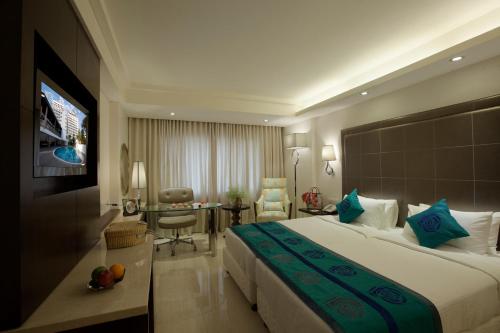 a hotel room with a large bed and a desk at Savera Hotel in Chennai