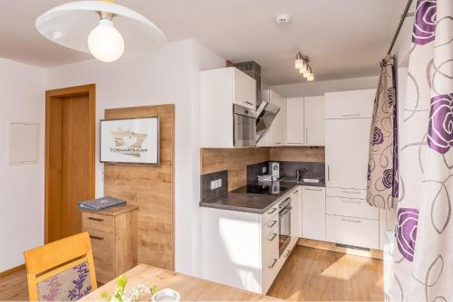 a kitchen with white cabinets and a wooden table at Tobhartbauer in Dorfgastein