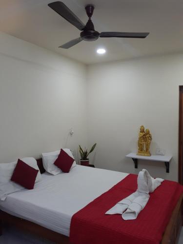 a white bed with red and white pillows and a ceiling fan at Nature Villa Kochi in Alwaye