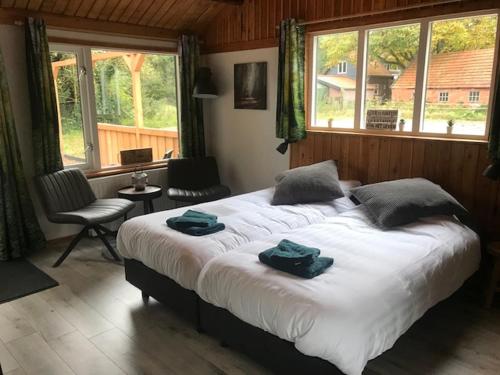 een slaapkamer met een groot bed en 2 handdoeken bij Veluwse Bossuite in Otterlo