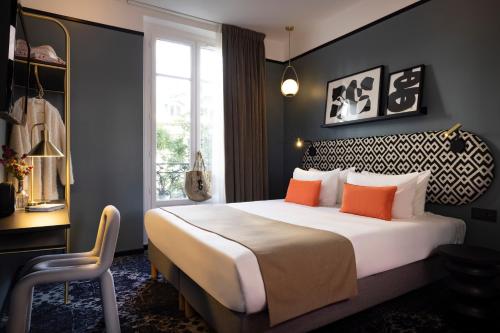 a bedroom with a large bed with orange pillows at Hôtel Palais De Chaillot in Paris