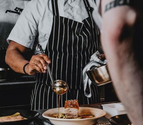 a man in a kitchen preparing a plate of food at Hotel Bellinzona Daylesford in Hepburn Springs