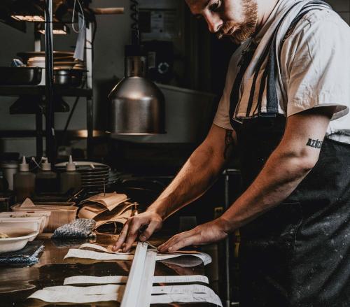a man standing in a kitchen preparing food at Hotel Bellinzona Daylesford in Hepburn Springs