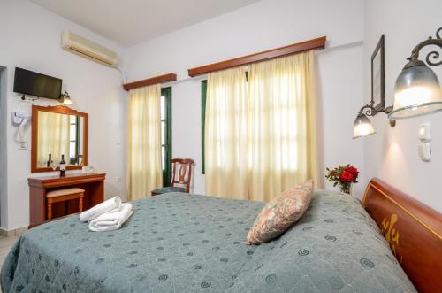 a bedroom with a bed with a blue comforter at Apollon Hotel in Naxos Chora