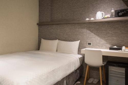 a bed in a room with a desk and a bed sidx sidx sidx at Cityinn Hotel Taipei Station Branch I in Taipei