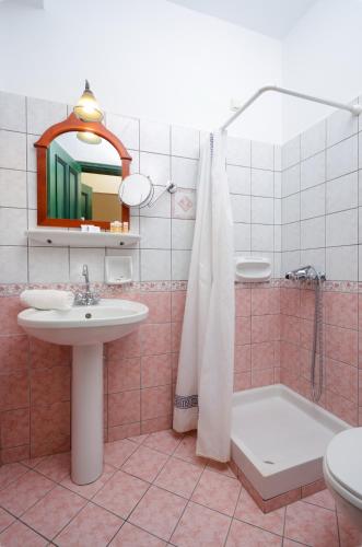 a bathroom with a sink and a mirror and a tub at Apollon Hotel in Naxos Chora