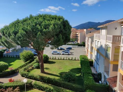 un complexe d'appartements avec un arbre dans un parking dans l'établissement Plein sud 142, climatisé, à Argelès-sur-Mer