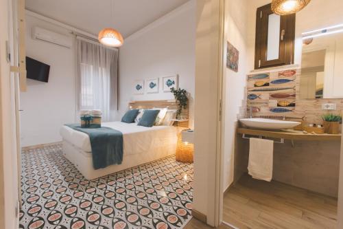 ein Schlafzimmer mit einem Bett und ein Badezimmer mit einem Waschbecken in der Unterkunft Le muse di Apollo in Syrakus