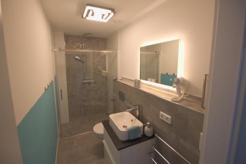 a bathroom with a sink and a shower with a mirror at Ferienwohnung Hegaublüte in Engen