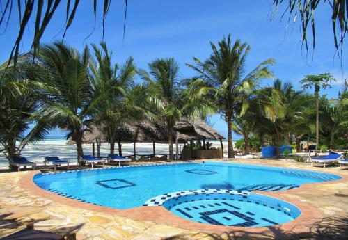 a swimming pool next to a beach with palm trees at Queen of Sheba Beach Lodge in Pongwe