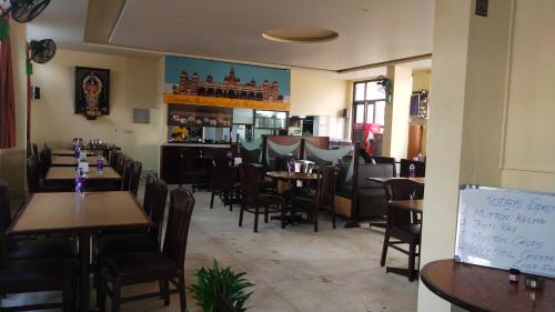 restauracja ze stołami i krzesłami oraz bar w obiekcie Hotel Vyshak International w mieście Mysuru