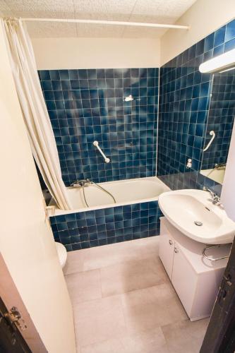 La salle de bains est pourvue de carrelage bleu, d'une baignoire et d'un lavabo. dans l'établissement Relai S11 Grand et lumineux studio avec coin montagne 4-6 pers, WIFI, 30m des pistes, grand balcon, DRAPS NON COMPRIS, à Saint-Jean-dʼAulps