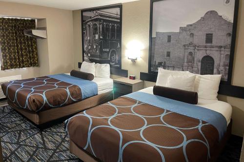 a hotel room with two beds and a picture on the wall at Super 8 by Wyndham San Antonio Downtown NE in San Antonio