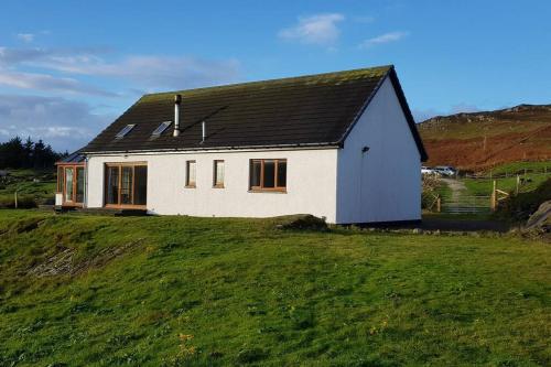 a white house on top of a grassy hill at Ocean Surf in Clashnessie