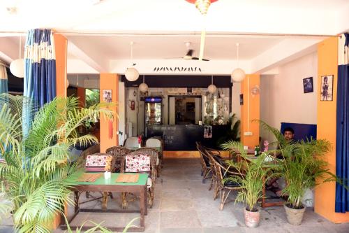 a restaurant with tables and chairs and plants at Maria Guest House in Palolem