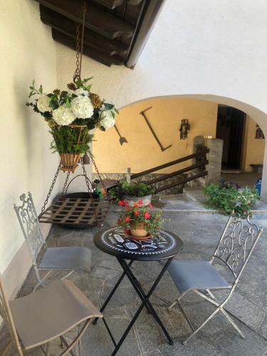 een patio met een tafel en stoelen en een klok bij Ancienne Maisonnette in Aosta