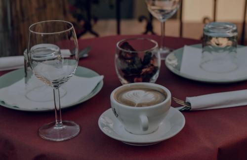 a table with a cup of coffee and wine glasses at Hotel Francesco in Pisa