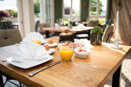 una mesa de madera con platos de comida y vasos de zumo de naranja en Hotel Johanneshof, en Oberstaufen