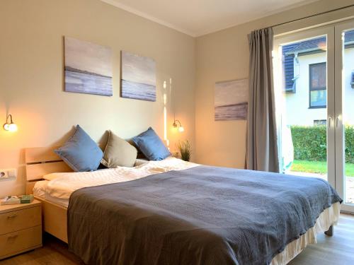 Un dormitorio con una cama con almohadas azules y una ventana en Blick ins Grüne- Premium-FeWo, en Göhren-Lebbin