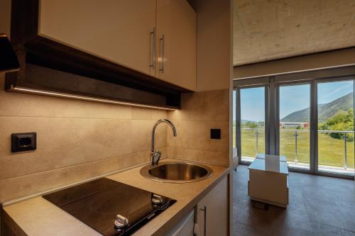 uma cozinha com um lavatório e uma grande janela em Apartmani Luka em Herceg Novi