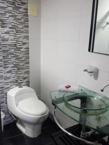 a bathroom with a toilet and a glass sink at Hermoso Apartamento Frente a la playa piso 17 Conquistador, el Laguito in Cartagena de Indias