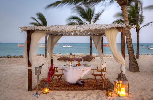 a table on the beach with a tent and lights at Billionaire Resort & Retreat Malindi in Malindi