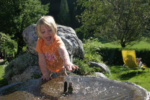 a little girl jumping into a water fountain at Ferienhof Grossgrub in Vorderstoder