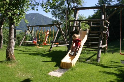 two children playing on a slide on a playground at Ferienhof Grossgrub in Vorderstoder