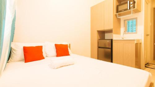 a bedroom with a white bed with orange and white pillows at Eimy's Place at Urban Deca Tower by RedDoorz in Manila