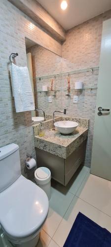 a bathroom with a white toilet and a sink at Flat Tabatinga Nord, vista para o mar in Conde