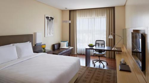 Pokój hotelowy z łóżkiem, biurkiem i telewizorem w obiekcie Courtyard by Marriott Bilaspur w mieście Bilaspur