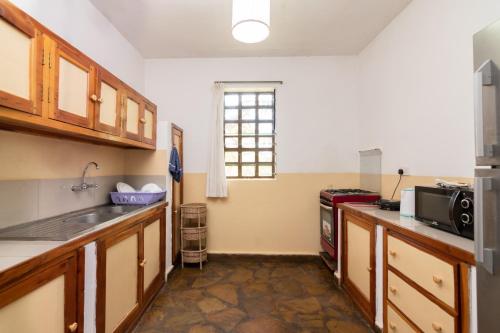 a kitchen with a sink and a microwave at Eden House Cottages in Malindi