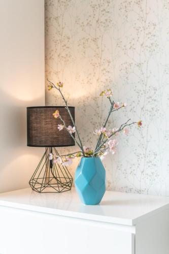 a blue vase on a white table with flowers in it at VilvoCity Center in Vilvoorde