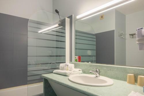 ein Bad mit einem Waschbecken und einem Spiegel in der Unterkunft As Hotel Orléans Nord Artenay in Artenay