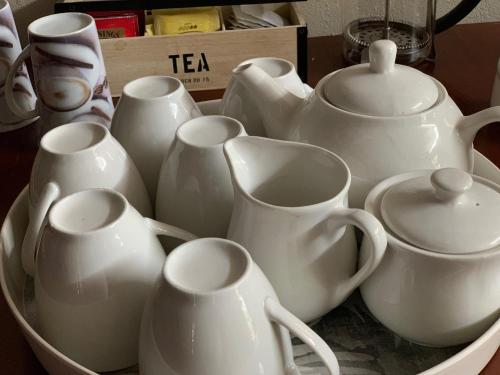 a group of white cups and teapots in a bowl at Sunset Guesthouse and Venue Cullinan in Meule
