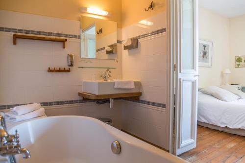 een badkamer met een bad en een bed bij Hotel Restaurant Les Tourelles in Le Crotoy