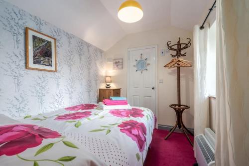 a bedroom with a bed with pink flowers on it at Coastal cottage 'The Garden Cottage ' in Hartland